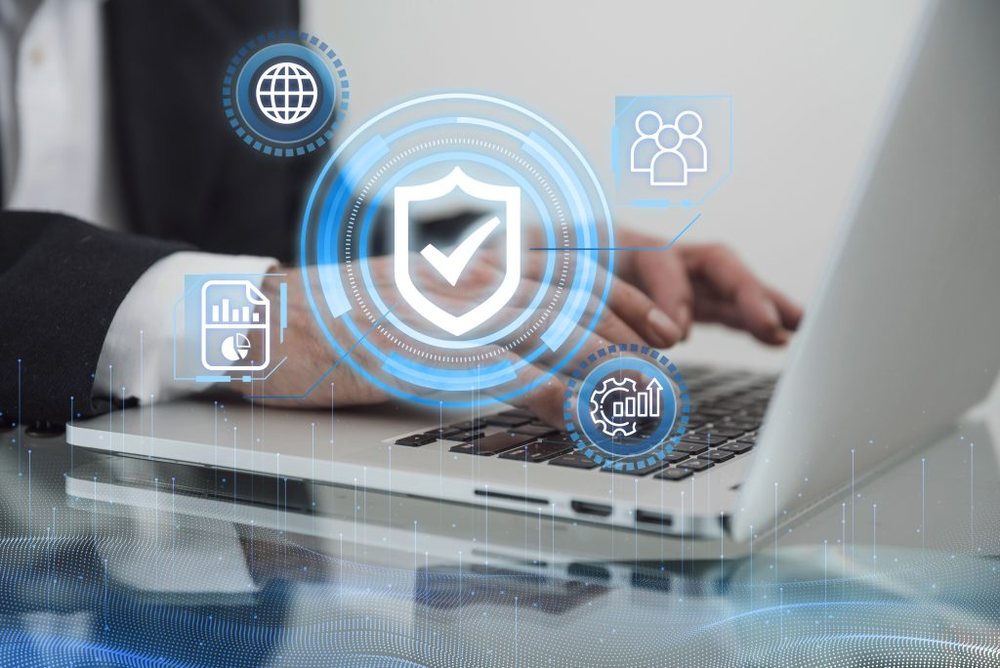 Hands typing on a laptop with security and analytics icons