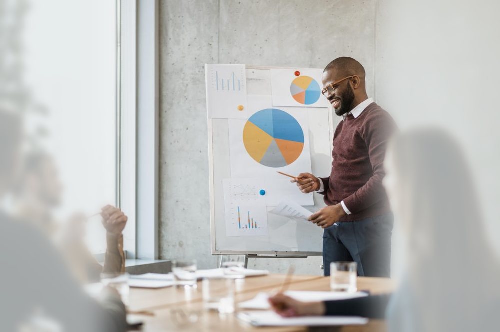 A trainer presenting charts to a team in a meeting room